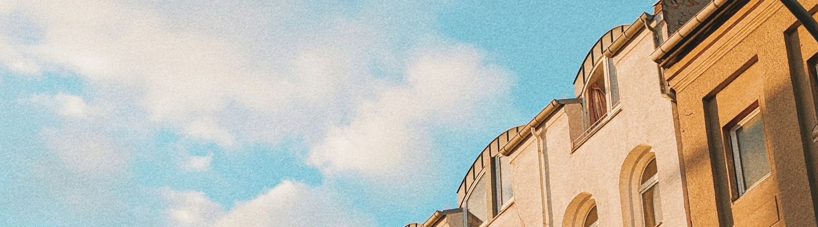  A low-angle view of a row of European-style buildings with balconies under a blue sky