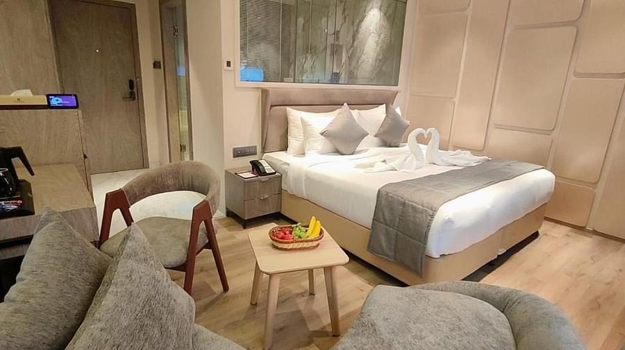 A side angle shot of Suit Room with a comfortable bed and a study desk and a comfy sofa at Maxxvaule Hotel, MIDC