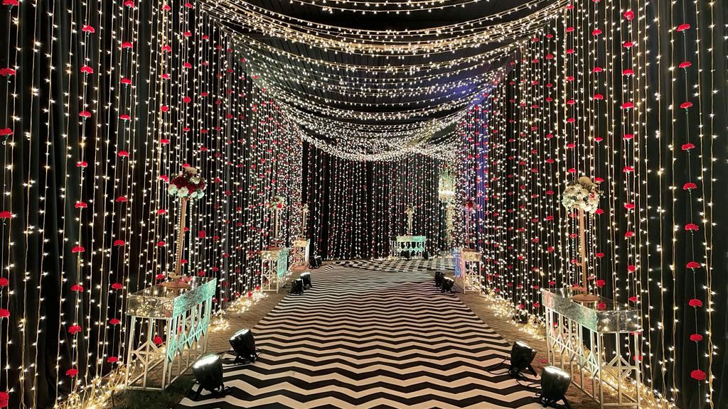 Beautifully decorated walkway with hanging lights and floral strings, creating an elegant festive entrance setup.