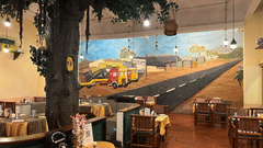 The Dhaba 1995, a dining area at the best resort in Bangalore, with tables, chairs, and a mural on the wall | Ramanashree California Resort