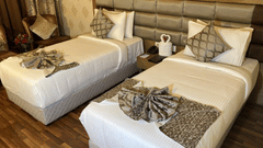 A hotel room with two single beds, each with decorative towels shaped like swans.