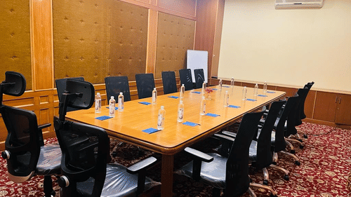 A conference room with a long table, chairs, and wood-paneled walls at best resort in Bangalore | Ramanashree California Resort