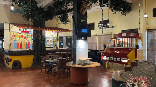 The bar area at Dhaba 1995, a dining area at the best resort in Bangalore, with tables, chairs, a sofa and a front of a decorated as a decoration | Ramanashree California Resort