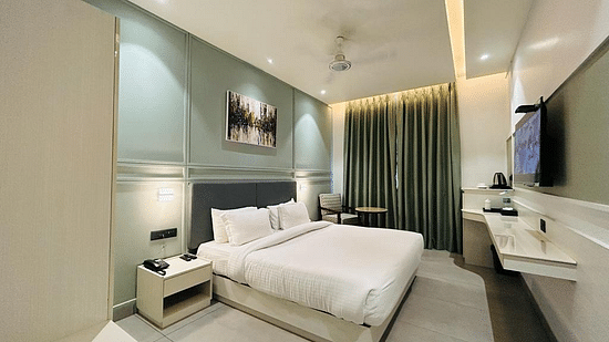 A well-arranged room with a tidy bed, wall art, a television, a tea & coffee maker and a comfortable sofa chair - Five Elements Hotels Goldleaf, Haldwani