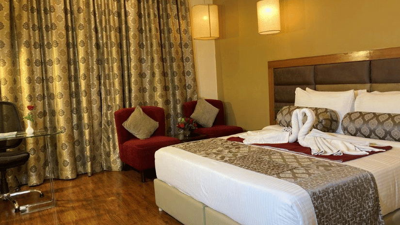 A hotel room with a bed and decorative towels shaped like swans.