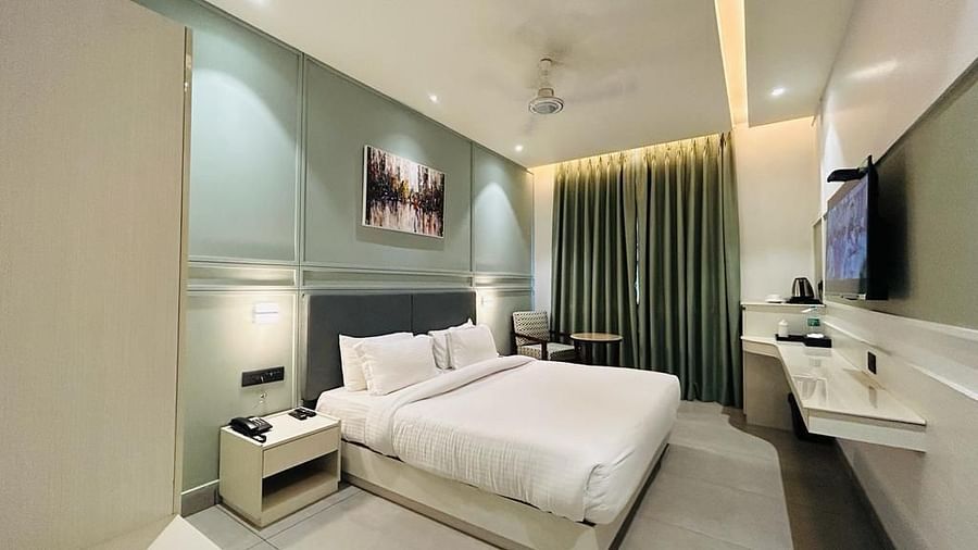 A well-arranged room with a tidy bed, wall art, a television, a tea & coffee maker and a comfortable sofa chair - Five Elements Hotels Goldleaf, Haldwani