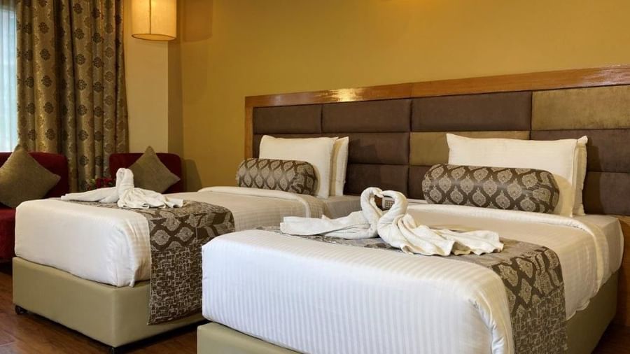 A hotel room with two beds and decorative towels shaped like swans.