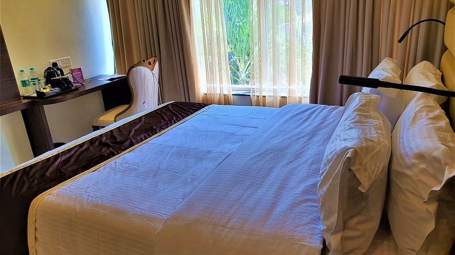 a double bed with study table and floor to ceiling window at VITS shanti solitaire, North Goa