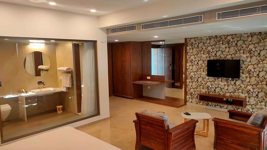 A view of our hotel room with a glass-door bathroom, stylish furniture, elegant decor, and a comfortable bed