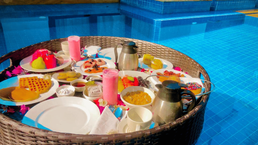 A huge basket containing several food items in it floating on the outdoor swimming pool.