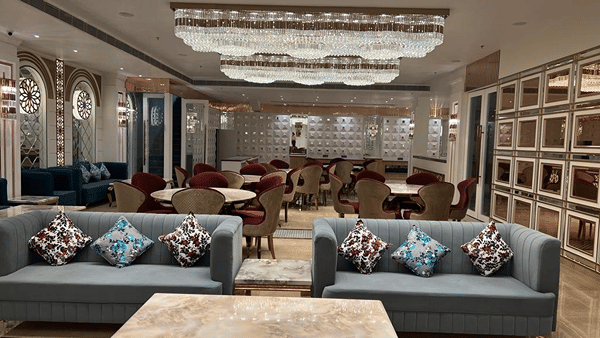 Reception setup with twin sofas under crystal chandeliers in the banquet hall.