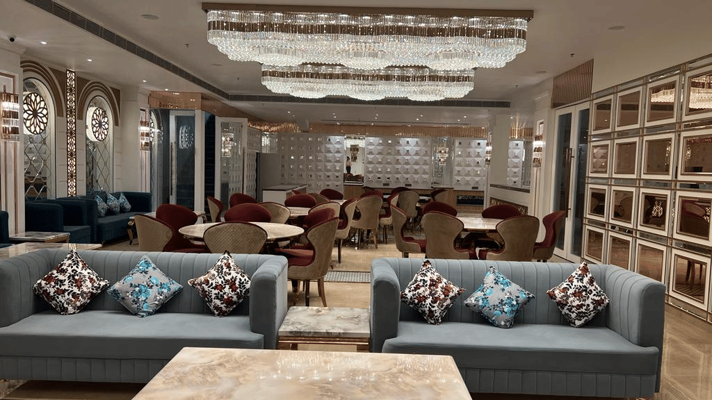 Reception setup with twin sofas under crystal chandeliers in the banquet hall.