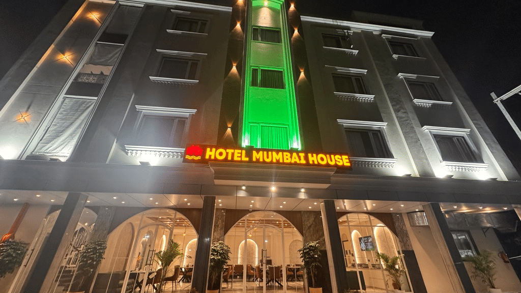 Illuminated hotel exterior with green vertical lighting and entrance façade at night in Pithampur.