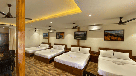 Spacious group accommodation featuring four double beds, wooden flooring, and warm recessed ceiling lighting - DAN Resorts & Weddings, Palghar