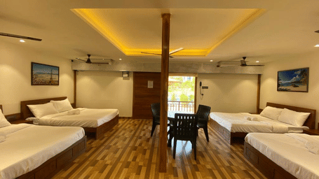 Large open-plan guest room with multiple beds, wooden accents, and an central architectural pillar - DAN Resorts & Weddings, Palghar