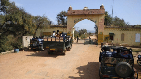 An overview of a entrance of Tehla safari gate with a canter and jeep in view near the entrance with many people on it near Utsav camp Sariska. A safari is possible during your day trip from Delhi to Sariska National Park.