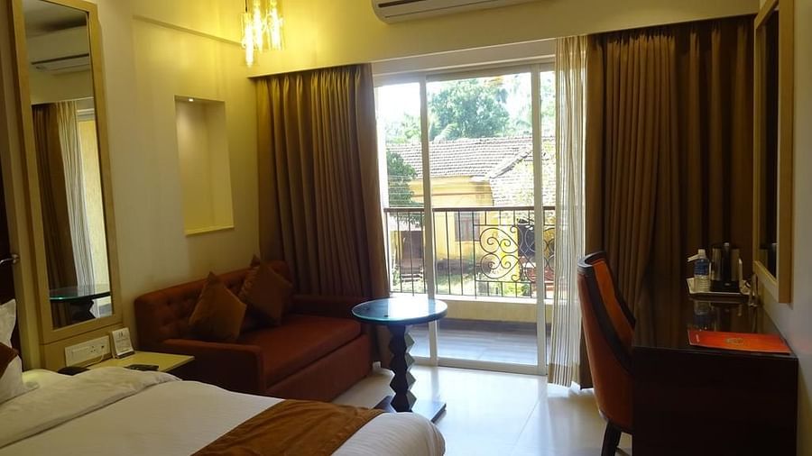 Image of a room with a bed and a balcony on the side at Calux Grand Inn, Calangute.