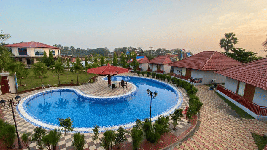 Large circular outdoor pool with paved walkways and surrounding resort villas - DAN Resorts & Weddings, Palghar