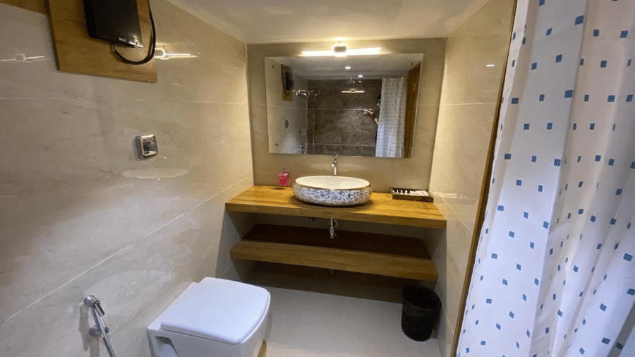 Clean bathroom interior with a vessel sink on a wooden counter and a large lighted mirror - DAN Resorts & Weddings, Palghar