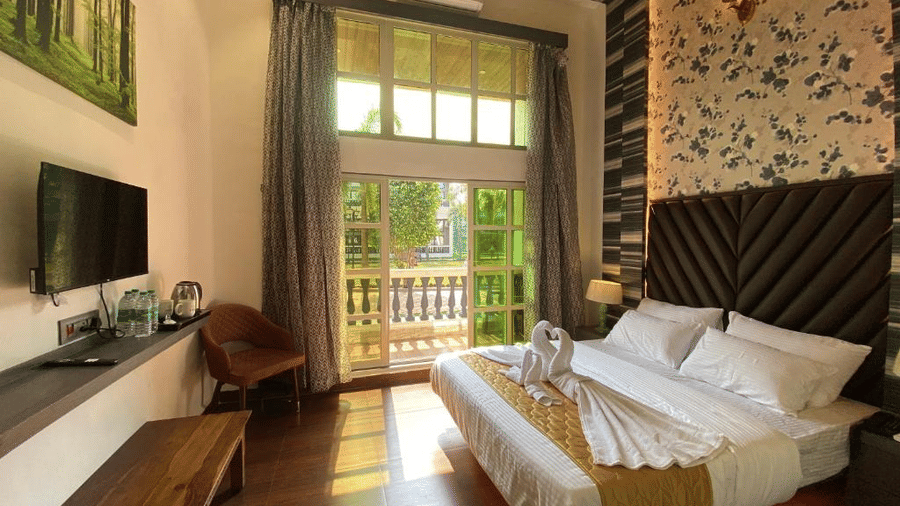 Sunlit premium room featuring a wall-mounted TV, decorative stone wall accents, and luxury bedding - DAN Resorts & Weddings, Palghar