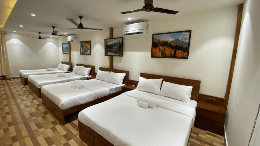 Large group accommodation room with multiple double beds arranged in a row for families - DAN Resorts & Weddings, Palghar