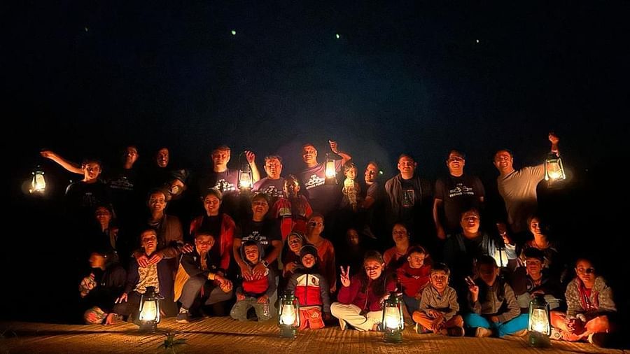 A large group of people of various ages holding lanterns at night, celebrating outdoors with a joyous pose - Evergreen County