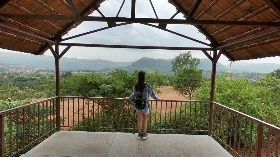 A guest enjoys the expansive view from a covered platform at Forest Escapes Koyna, overlooking the hills.