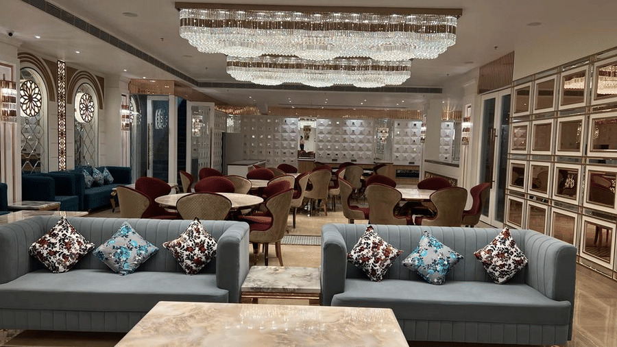 Wedding hall with two plus looking twin sofa and a wooden table, all underneath a ceiling covered with crystal chandeliers.