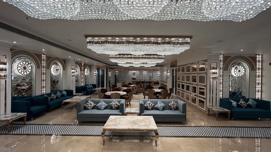 Wedding hall with two plus looking twin sofa and a wooden table, all underneath a ceiling covered with crystal chandeliers.