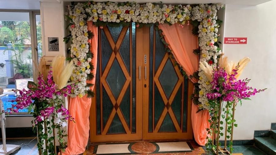 Wooden banquet door decorated with drapes and vibrant flowers, welcoming guests into the event space at Mayur Retreat.