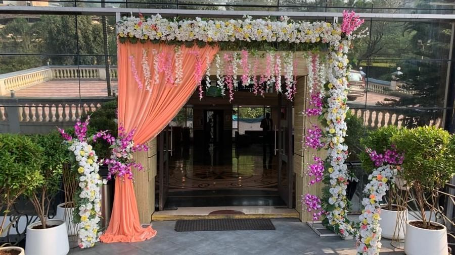 Decorated entrance of the banquet hall at Mayur Retreat, adorned with orange drapes and fresh floral arrangements.