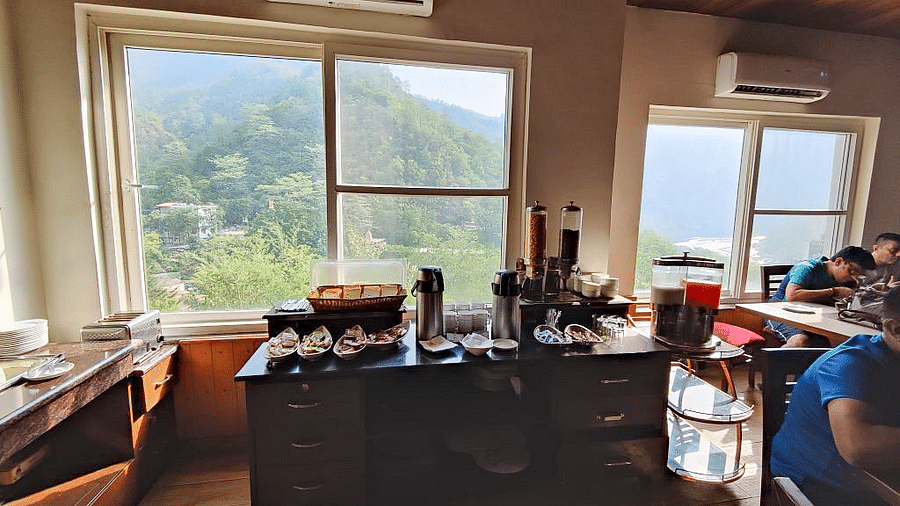 A wooden table with several bowls and tea and coffee flasks kept on it at Regenta Inn DLS.