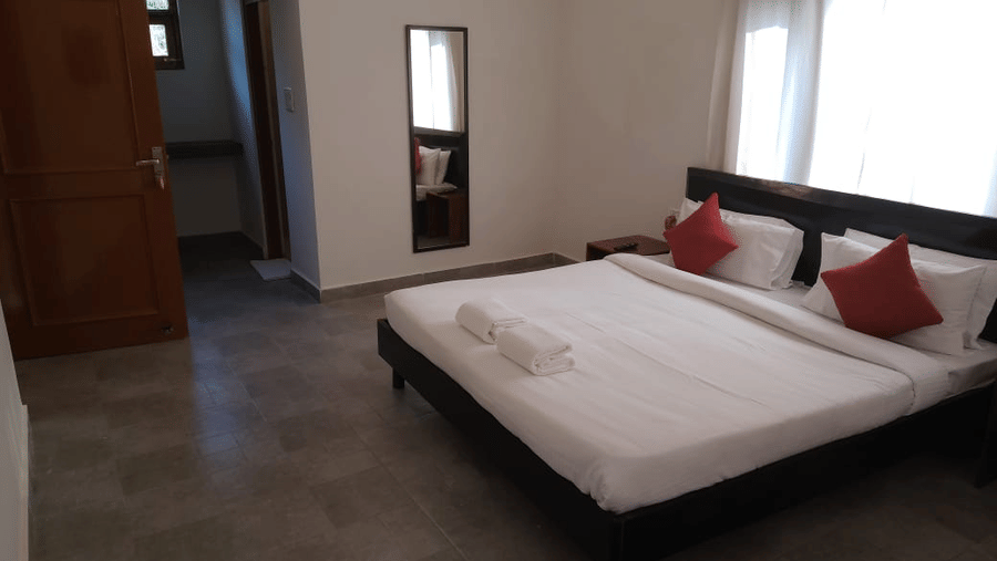 Spacious guest room with a king size bed, red accent cushions, seating area and large windows.