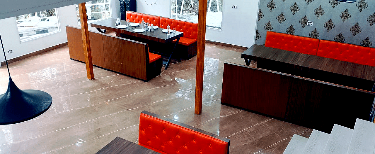 The interiors of the restaurant at DLS Nature Trinket Resort with red couches and tables.
