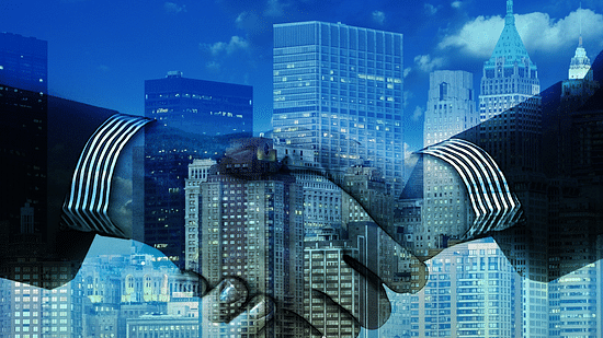Two people shaking hands with buildings overlapping on the image