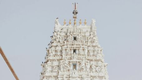 A traditional white Indian temple with intricate carvings and a golden archway in Rajasthan, India.