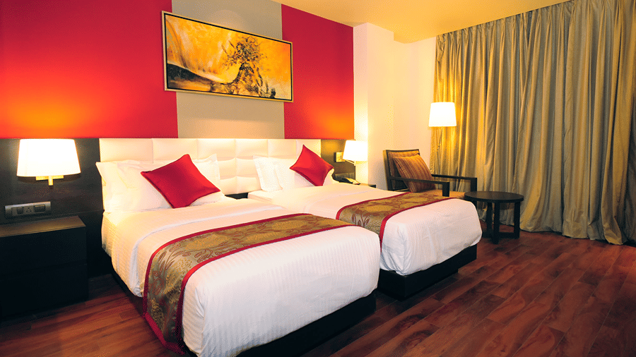 Two single beds in an Executive Room along with an arm chair and a small coffee table in the corner of the room - Senses Hotel
