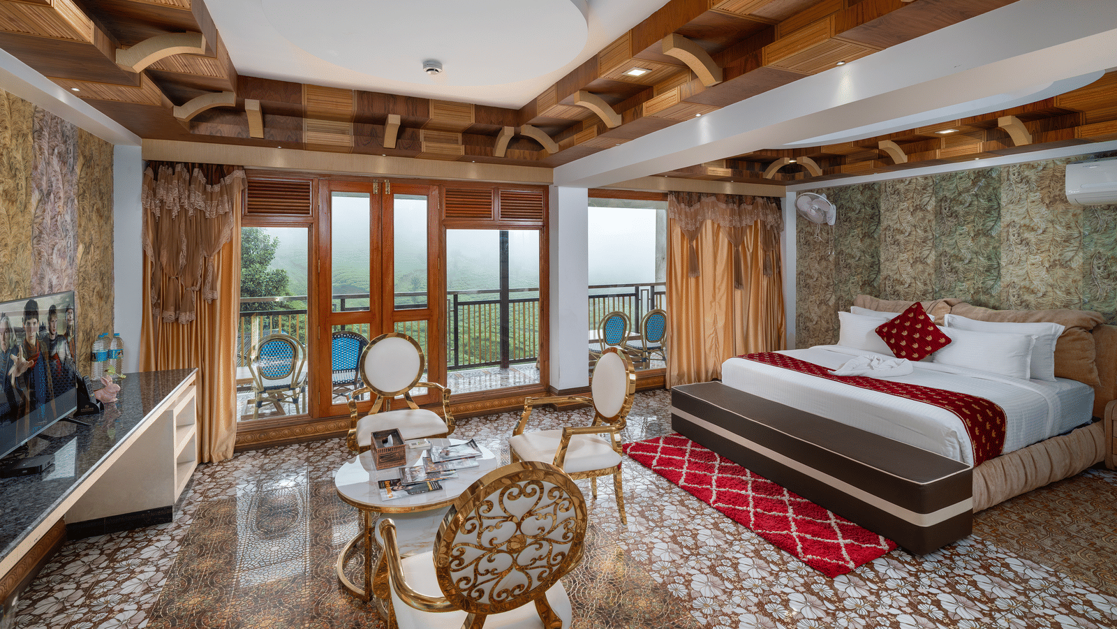 The expansive bedroom of the Presidential Suite at Parakkat Nature Hotel and Resorts, Munnar, featuring a large bed, decorative wooden-beam ceilings, a seating area with a table, and glass doors opening to a scenic view.
