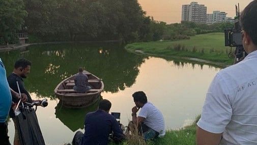 A lake surrounded by greenery while people are working for a photoshoot - Karma Lakelands, Gurgaon