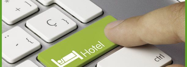 A finger pressing a hotel booking key on a white keyboard.