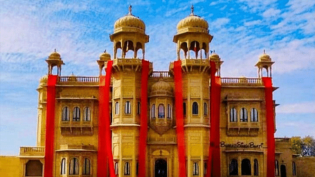 A facade image of Jawahar Niwas Palace with red coloured decoration carpets hing from the pillars