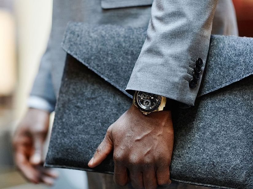 A man in a grey jacket holding a file - S Hotel Kingston, Jamaica