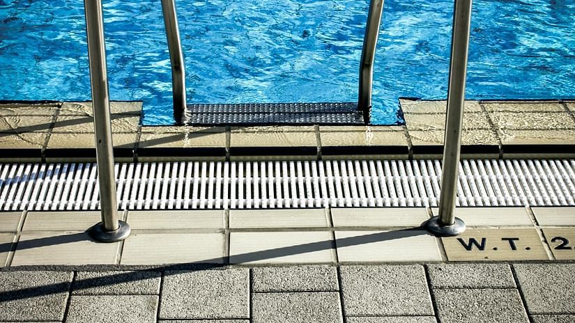 A metallic rail is visible next to the edge of a swimming pool.
