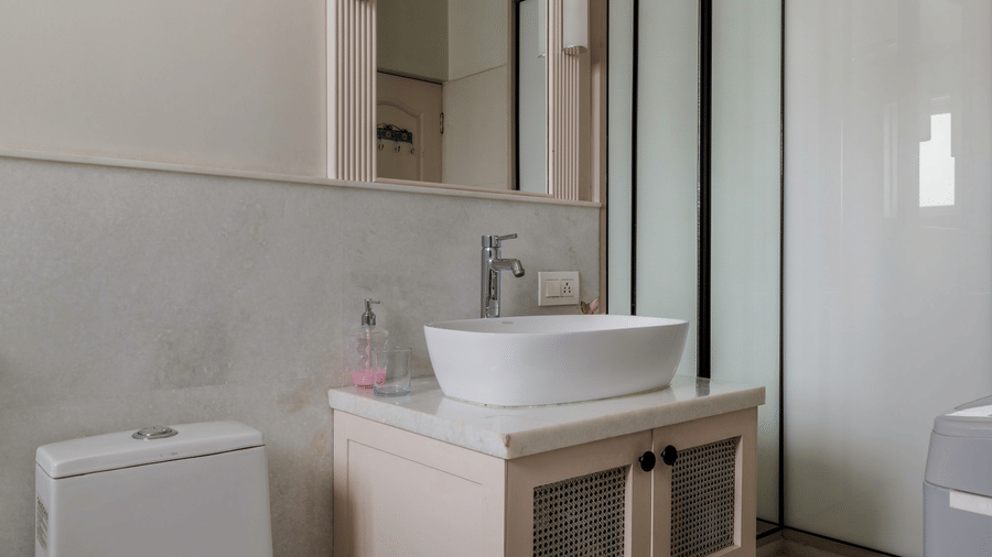 Bathroom with a wall-mounted toilet, a wash basin, and a large mirror at Barwara Kothi, Jaipur.