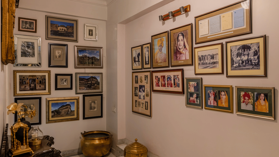 Narrow gallery corridor with rows of framed photographs, a pendant light, and striped flooring at Barwara Kotha, Jaipur.