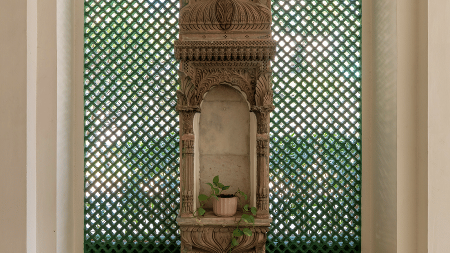 Room with an ornate green jaali arched alcove, a wall shelf, and dark wooden flooring at Barwara Kothi, Jaipur.