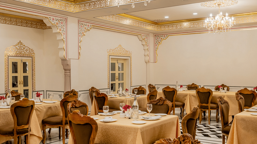 side view image of the dining area with well arranged crockery along with a small flower vase with rose kept in it - Brij Castle, Jaipur