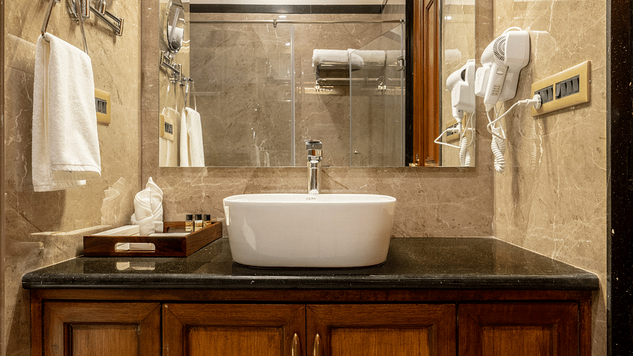 a wash basin with a covered vanity area along with a huge square shaped mirror - Brij Castle, Jaipur