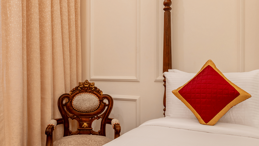 a cushioned armchair placed in the corner of the room besides a single bed - Brij Castle, Jaipur