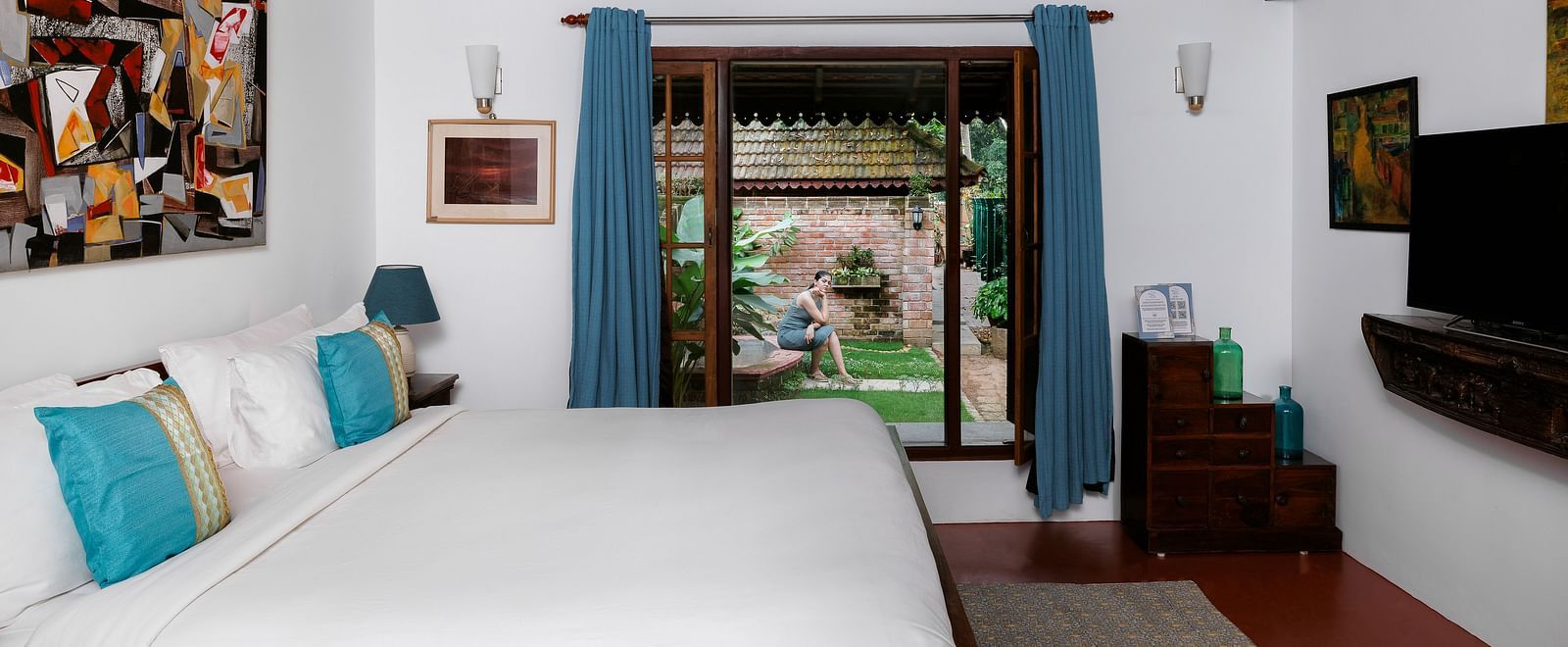 A shot of a room with bed, a flat screen TV, and a window overlooking the view - BluSalzz Villas - Muhamma Resort, Alleppey